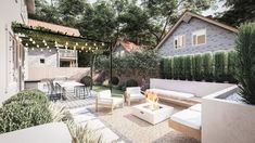 an outdoor living area with white furniture and string lights strung over the fire pit, surrounded by greenery