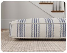 a blue and white striped pillow sitting on top of a floor next to a stair case