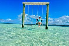 a woman sitting on a swing in the ocean