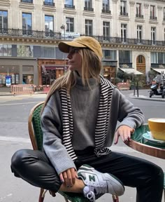 a woman sitting on top of a green chair in front of a tall building with lots of windows