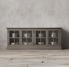 an old wooden cabinet with glass doors and dishes on it