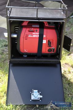 a red and black portable generator sitting on top of a metal box in the grass