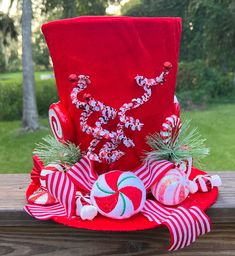 a red christmas hat with candy canes and candies on the top is sitting on a wooden table