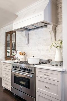 a stove top oven sitting inside of a kitchen next to white cabinets and counter tops