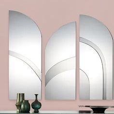 three mirrors are on the wall near vases