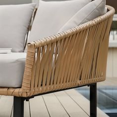 two wicker chairs sitting next to each other on a wooden deck with white pillows