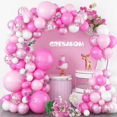 there is a pink and white cake surrounded by balloons, flowers, and other decorations