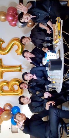 the men are posing for a photo in front of some balloons and letters that read 35