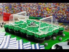 cupcakes decorated with green frosting and soccer balls on a table in front of a colorful wall