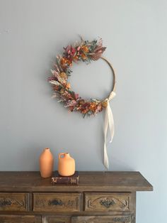 a wreath on top of a dresser next to vases