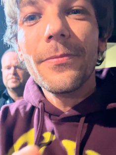 a close up of a person wearing a purple shirt and holding something in his hand