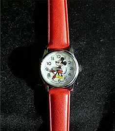 a red watch with mickey mouse on it's face sitting on a black surface