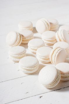 white macaroons are scattered on a white wooden surface