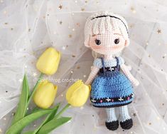 a crocheted doll next to tulips on a white background with stars