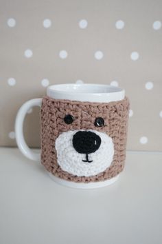 a crocheted coffee mug with a bear's face on the front and sides