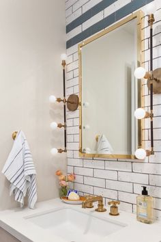 a bathroom with a sink, mirror and lights on the brick wall above it's counter