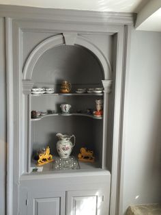 a white china cabinet with shelves and dishes on it