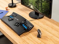 a computer keyboard sitting on top of a wooden desk next to a mouse and monitor