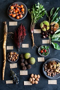 an assortment of fruits and vegetables displayed in bowls on a black surface with name tags