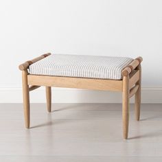 a wooden bench sitting on top of a hard wood floor next to a white wall