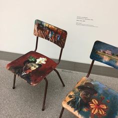 two chairs with paintings on them sitting next to each other