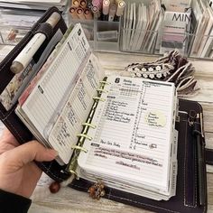 a person is holding an open planner book in front of other items on a table