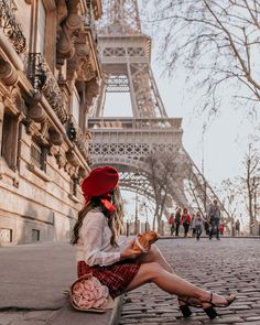 a woman sitting on the ground in front of the eiffel tower, eating bread