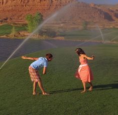 two children playing with a sprinkler in the grass