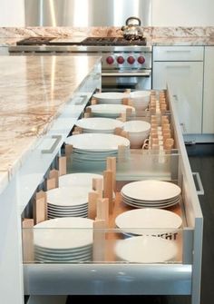 an open drawer in the middle of a kitchen with plates and bowls on it's side