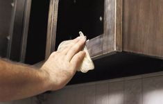 a man cleaning the inside of a microwave oven with a cloth on it's mitt