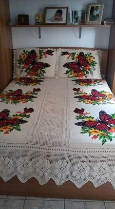 a bed with a white bedspread covered in flowers and butterfly appliques