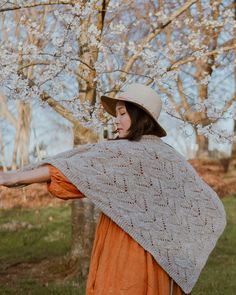 a woman in an orange dress and hat holding a shawl