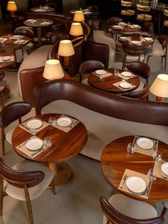 an empty restaurant with wooden tables and brown leather booths, white plates and silverware