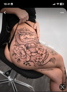 a woman with a dragon tattoo on her stomach sitting in a chair and holding onto the side of her body