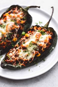 two stuffed peppers on a white plate with parmesan cheese and other toppings