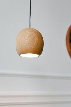 a wooden light hanging from the ceiling in a room with white walls and wood trim