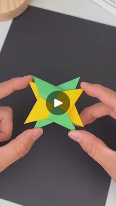 two hands holding origami stars on top of a table