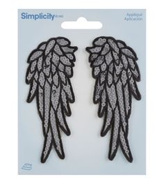 two black and white angel wings with sparkles on the wings are in front of a card