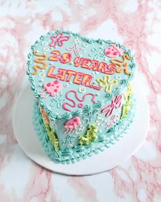 a decorated cake sitting on top of a white plate next to a pink marble counter