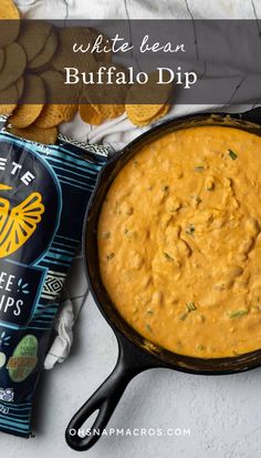 white bean buffalo dip in a cast iron skillet next to chips