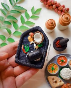 a hand holding a miniature tray with food on it