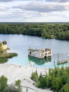 an old building sitting on top of a lake surrounded by trees and other green plants