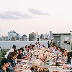 a group of people sitting at a long table with food and drinks in front of them