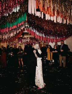 a man and woman dance in front of a large amount of streamers hanging from the ceiling