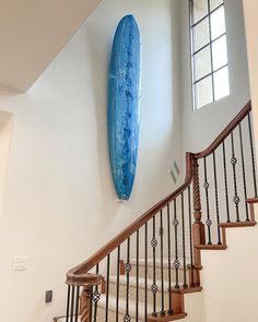 a blue surfboard hanging on the wall next to a stair case in a house