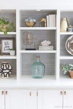 a white bookcase filled with lots of books and vases on top of it