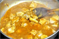 a wooden spoon is stirring some food in a pot with broth and meats