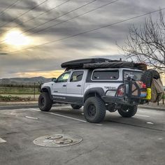 the truck is parked on the side of the road with its roof open and luggage strapped to it's back