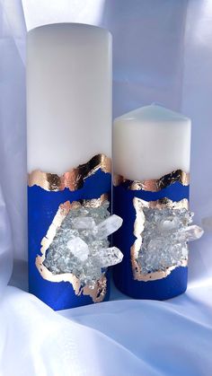 two white candles with blue and gold designs on them