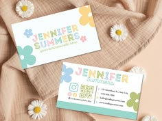 two business cards sitting next to each other on top of a bed covered in flowers